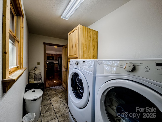 clothes washing area with cabinets, a textured ceiling, and independent washer and dryer