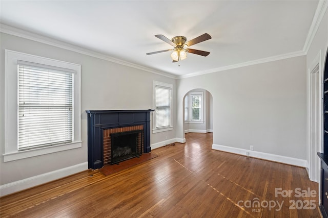 unfurnished living room featuring ornamental molding, a brick fireplace, dark hardwood / wood-style floors, and ceiling fan