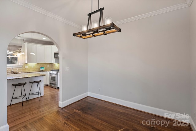 unfurnished dining area with an inviting chandelier, crown molding, and dark wood-type flooring