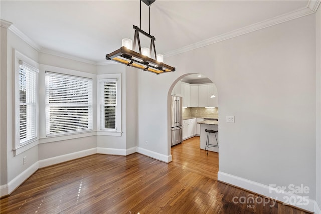 unfurnished dining area with a notable chandelier, crown molding, and hardwood / wood-style floors