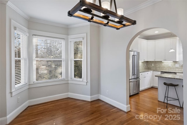 kitchen featuring high quality fridge, decorative light fixtures, white cabinetry, backsplash, and crown molding