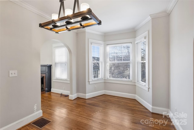 interior space featuring plenty of natural light, ornamental molding, wood-type flooring, and a notable chandelier