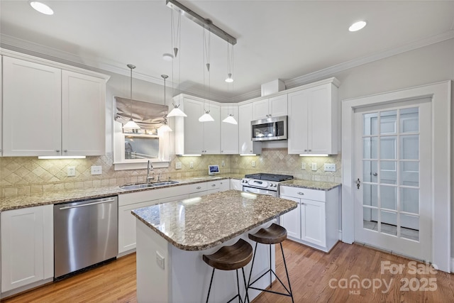 kitchen with sink, decorative light fixtures, stainless steel appliances, light stone countertops, and white cabinets