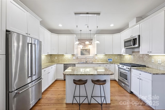 kitchen with pendant lighting, white cabinetry, stainless steel appliances, and a kitchen island