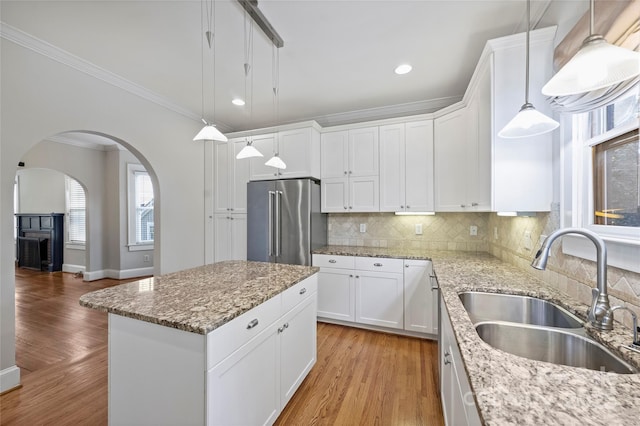 kitchen featuring sink, white cabinetry, high end refrigerator, a kitchen island, and light stone countertops