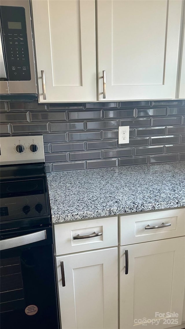 kitchen featuring white cabinetry, range with electric cooktop, tasteful backsplash, and light stone countertops