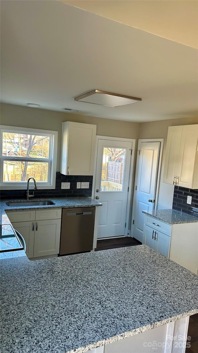 kitchen featuring white cabinetry, backsplash, dishwasher, light stone countertops, and sink