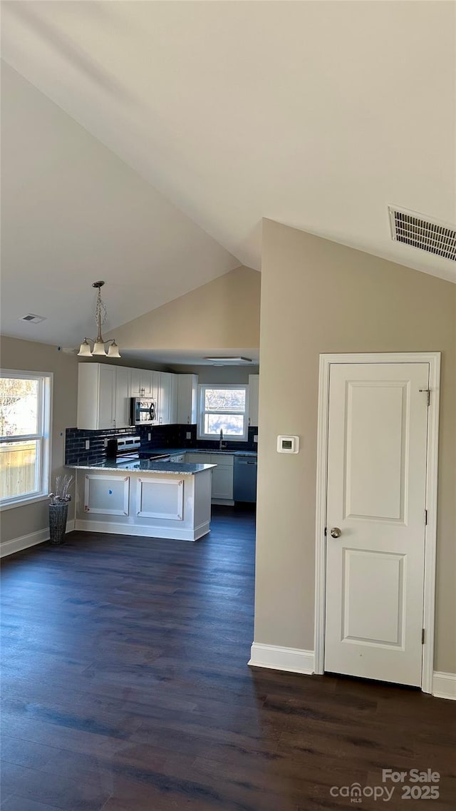 kitchen featuring appliances with stainless steel finishes, lofted ceiling, dark wood-type flooring, hanging light fixtures, and kitchen peninsula