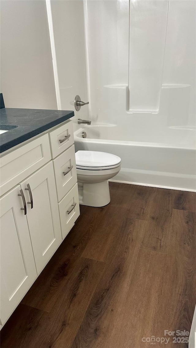 full bathroom with hardwood / wood-style flooring, toilet, vanity, and shower / bathtub combination