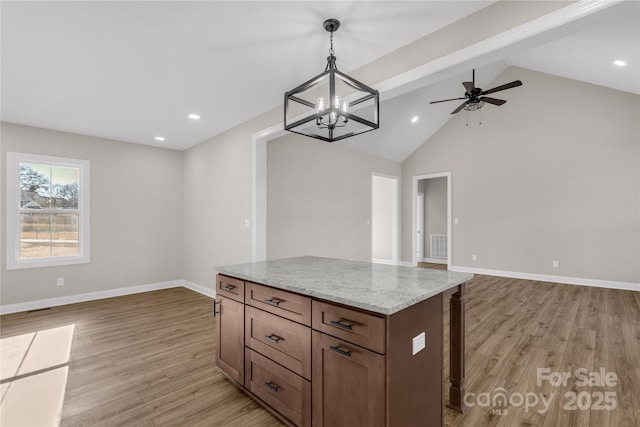 kitchen with light hardwood / wood-style floors, decorative light fixtures, vaulted ceiling with beams, a kitchen island, and light stone counters