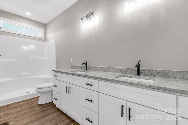 bathroom with toilet, a shower, hardwood / wood-style flooring, and vanity