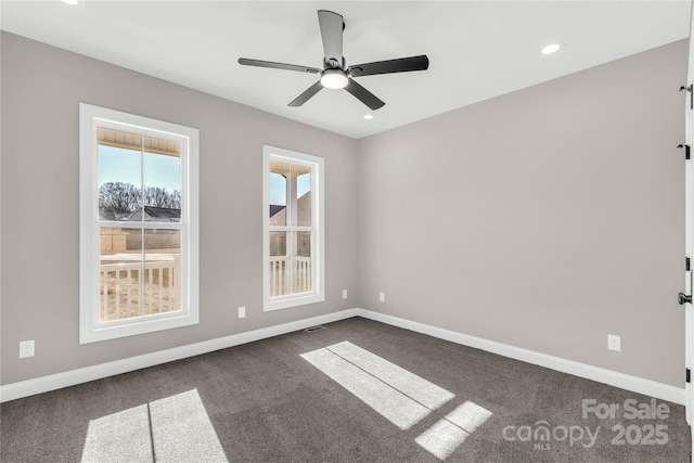 empty room with ceiling fan and dark colored carpet