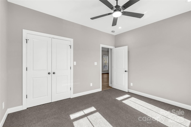 unfurnished bedroom with ceiling fan, dark carpet, and a closet