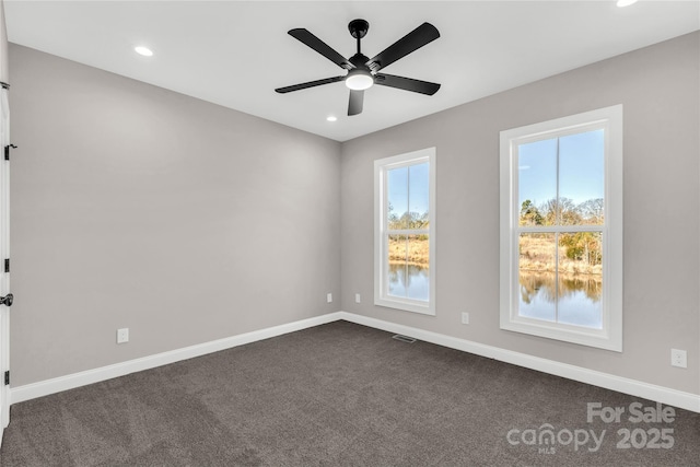 unfurnished room with dark colored carpet and ceiling fan