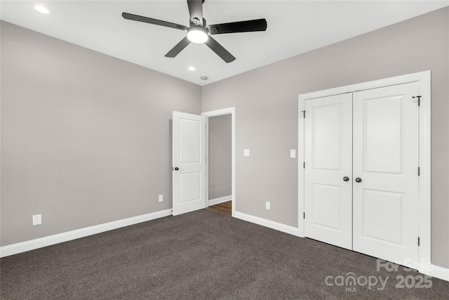 unfurnished bedroom with ceiling fan, dark carpet, and a closet