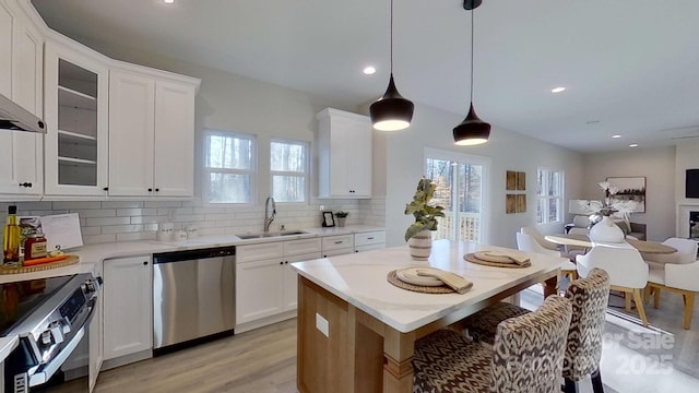 kitchen featuring white cabinetry, appliances with stainless steel finishes, sink, and hanging light fixtures