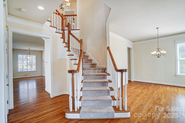 stairway with crown molding, baseboards, a chandelier, and wood finished floors