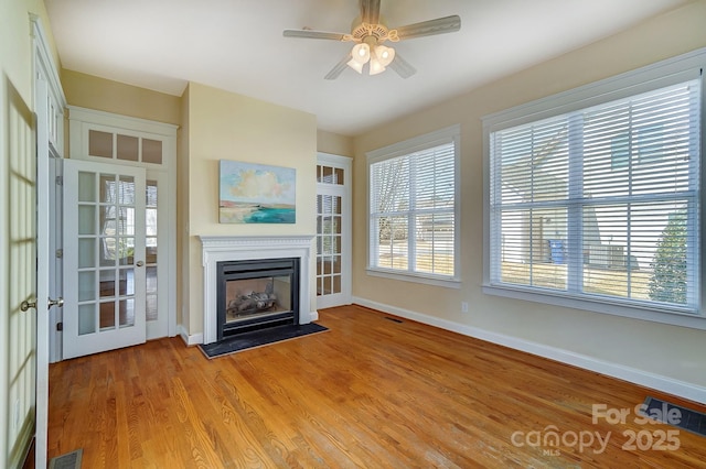 unfurnished living room with light wood-type flooring, a fireplace, visible vents, and baseboards