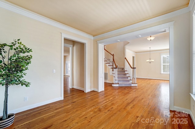 foyer entrance with a notable chandelier, wood finished floors, visible vents, stairs, and ornamental molding