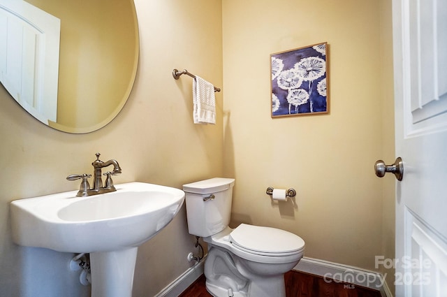 half bath with wood finished floors, toilet, and baseboards