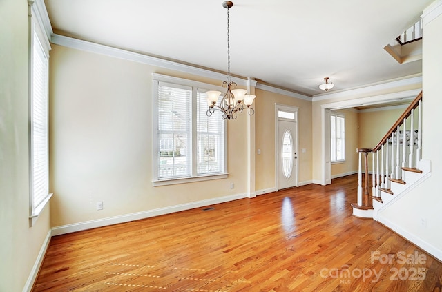 foyer entrance featuring baseboards, an inviting chandelier, stairs, crown molding, and light wood-type flooring