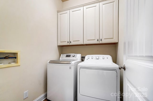 clothes washing area with separate washer and dryer and cabinet space