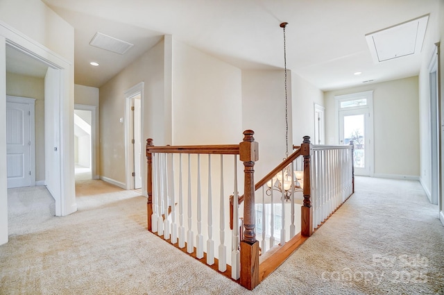 corridor with light carpet, attic access, visible vents, and an upstairs landing