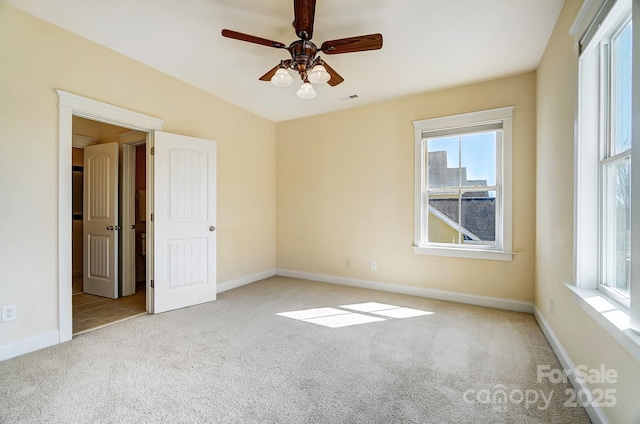 spare room featuring light carpet, baseboards, visible vents, and ceiling fan