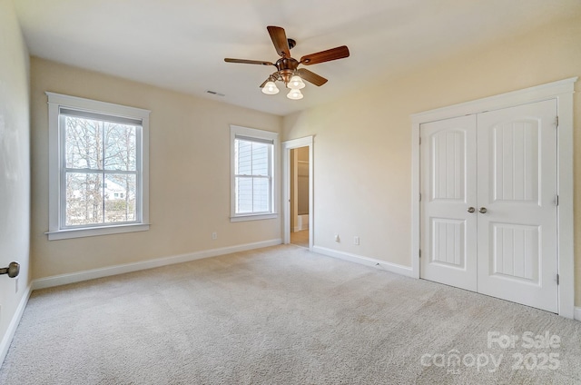 unfurnished bedroom featuring a closet, visible vents, light carpet, ceiling fan, and baseboards