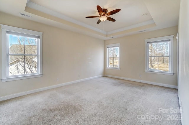 empty room with a wealth of natural light, a tray ceiling, and visible vents