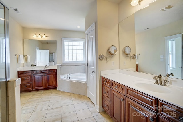 full bath featuring visible vents, a sink, and a garden tub