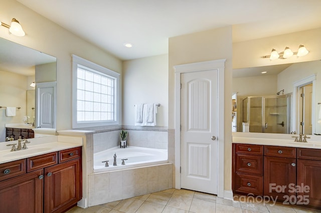 bathroom featuring a sink, a garden tub, tile patterned flooring, a shower stall, and two vanities