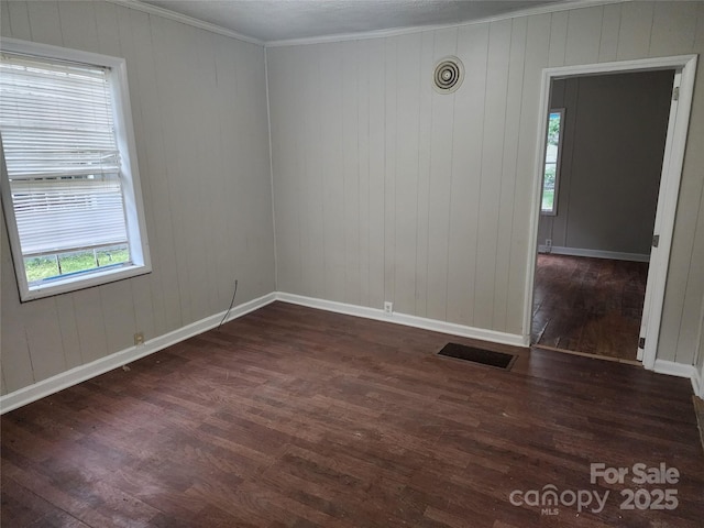 empty room with dark wood-type flooring and crown molding