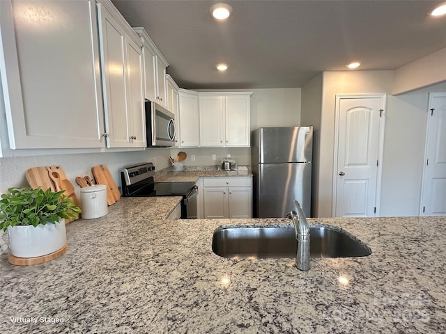 kitchen featuring light stone countertops, white cabinets, appliances with stainless steel finishes, and sink