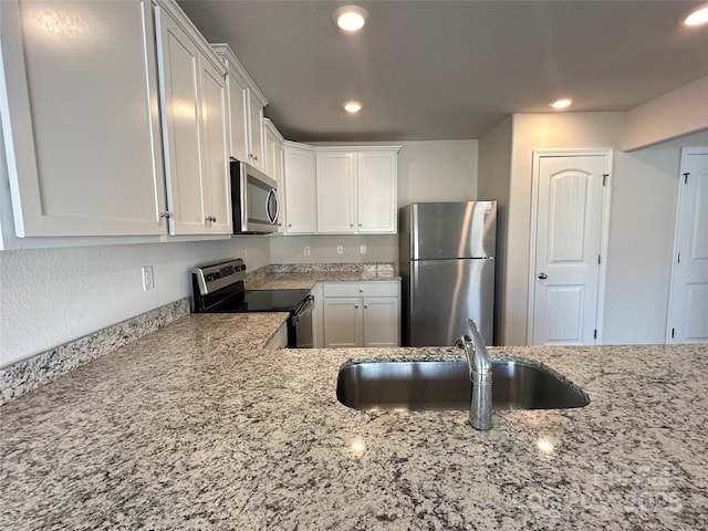 kitchen with light stone countertops, sink, white cabinets, and stainless steel appliances