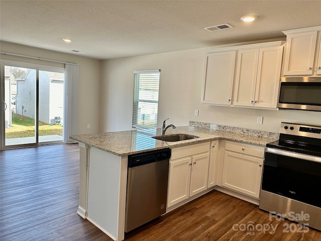 kitchen featuring light stone countertops, white cabinets, stainless steel appliances, sink, and kitchen peninsula