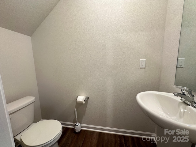 bathroom with toilet, vaulted ceiling, sink, and hardwood / wood-style floors