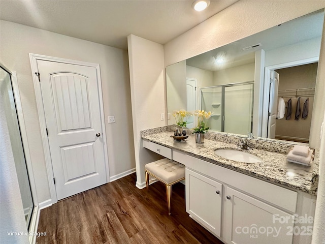 bathroom featuring a shower with shower door, hardwood / wood-style floors, and vanity