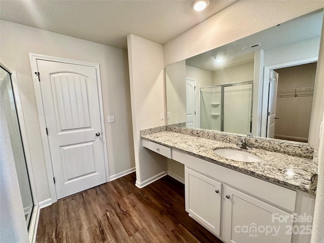 bathroom with hardwood / wood-style floors, an enclosed shower, and vanity