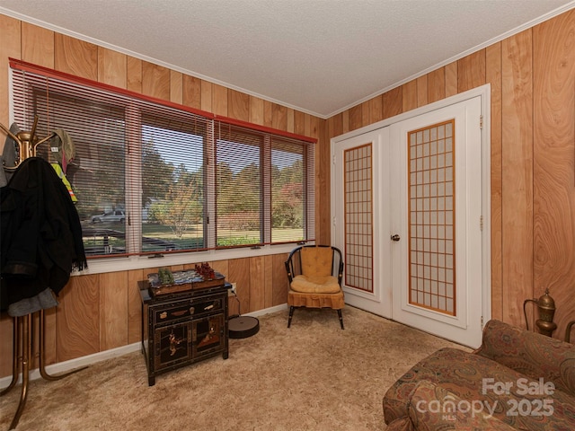 living area featuring light carpet, ornamental molding, wood walls, and french doors