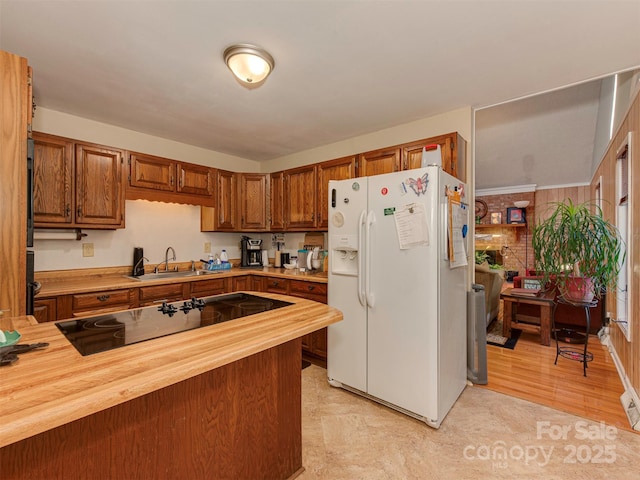 kitchen featuring white refrigerator with ice dispenser, butcher block counters, light hardwood / wood-style floors, sink, and black electric cooktop