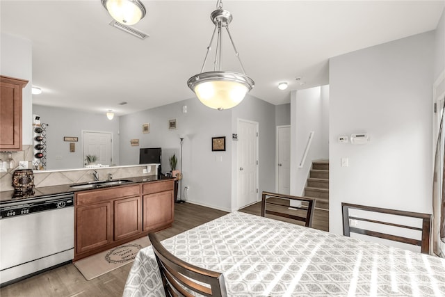 kitchen with pendant lighting, dishwasher, dark wood-type flooring, tasteful backsplash, and sink