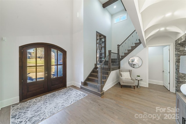 foyer with a high ceiling, french doors, and light wood-type flooring