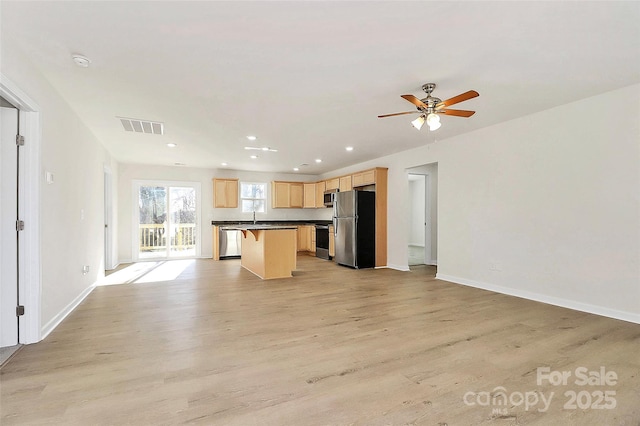 kitchen with stainless steel appliances, light wood-type flooring, light brown cabinetry, a breakfast bar, and a center island