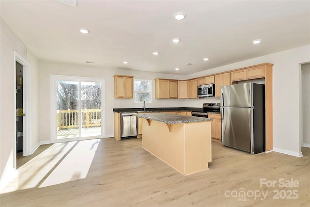 kitchen with light hardwood / wood-style floors, a kitchen island, a breakfast bar, sink, and appliances with stainless steel finishes