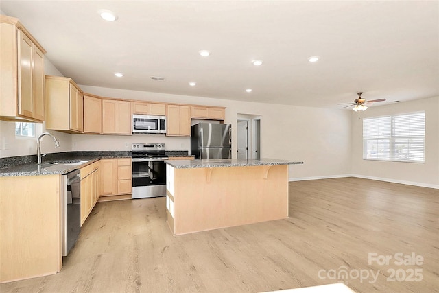 kitchen featuring ceiling fan, appliances with stainless steel finishes, a kitchen island, light hardwood / wood-style flooring, and sink