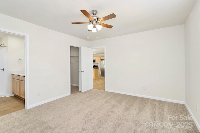 unfurnished bedroom featuring ensuite bath, stainless steel fridge, a closet, and light carpet