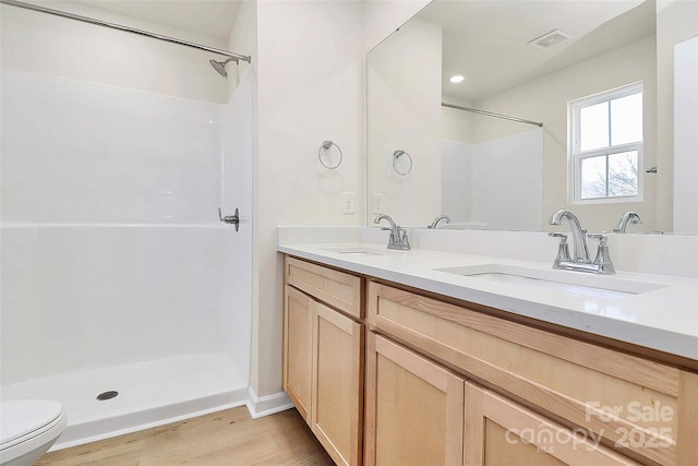 bathroom featuring walk in shower, vanity, toilet, and hardwood / wood-style floors