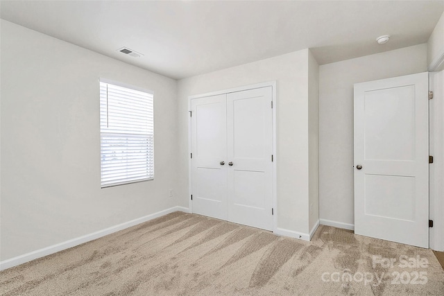 unfurnished bedroom featuring light colored carpet and a closet