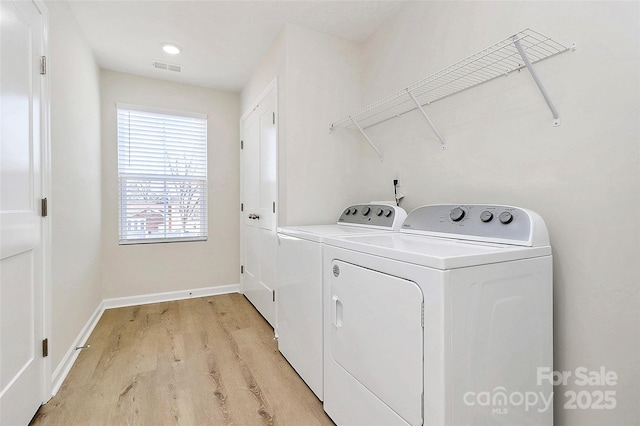 clothes washing area featuring washing machine and dryer and light hardwood / wood-style flooring